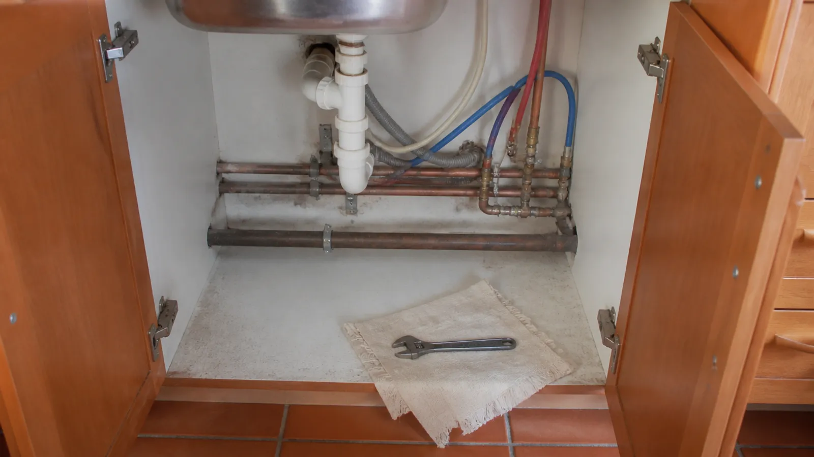 Mueble de cocina abierto con tuberías de cobre y herramientas para un trabajo general de fontanería en La Manga